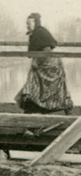 Photo d'une dame en costume local franchissant
    d'un bon pas la passerelle de l'écluse du canal à Ham en 1914-1918.
