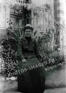 Photo d'une femme assise devant une maison.