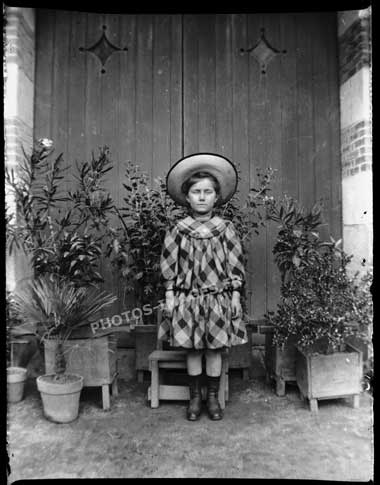 Photo d'une petite fille debout dans l'ambrasure d'une porte.