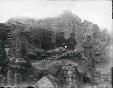 Photo de 5 soldats qui cassent la croûte à l'abri d'une maison en ruine pendant la guerre de 14-18