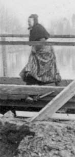 Photo d'une dame en costume local franchissant d'un bon pas la passerelle de l'écluse du canal Ham en 1914-1918.